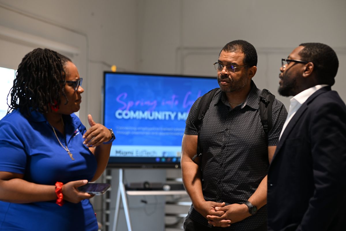 A Project SECURE mentor talking with two attendees at a community event
